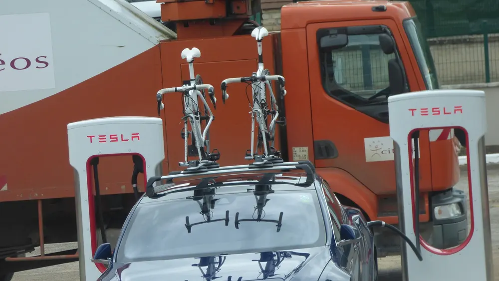 Tesla Model S mit zwei Rennrädern auf dem Dachträger an Tesla-Ladesäulen in Beaune (Frankreich)