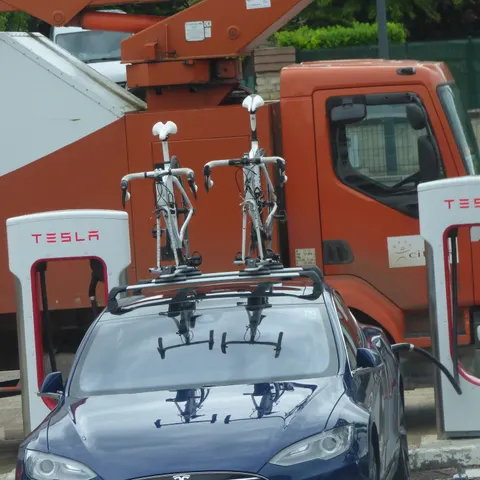Tesla Model S mit zwei Rennrädern auf dem Dachträger an Tesla-Ladesäulen in Beaune (Frankreich)