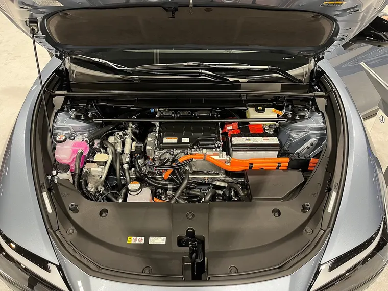 Geöffnete Fronthaube eines Elektroautos (Lexus RZ 450e): rechts die 12-Volt-Batterie, davor orangefarbene Hochvoltleitungen