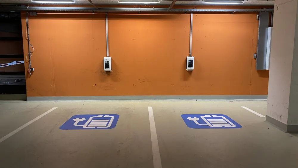 Zwei Wallboxen an der Wand einer Tiefgarage über zwei markierten Ladestellplätzen