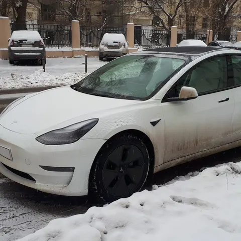 Weißes Tesla am verschneiten Straßenrand im Winter