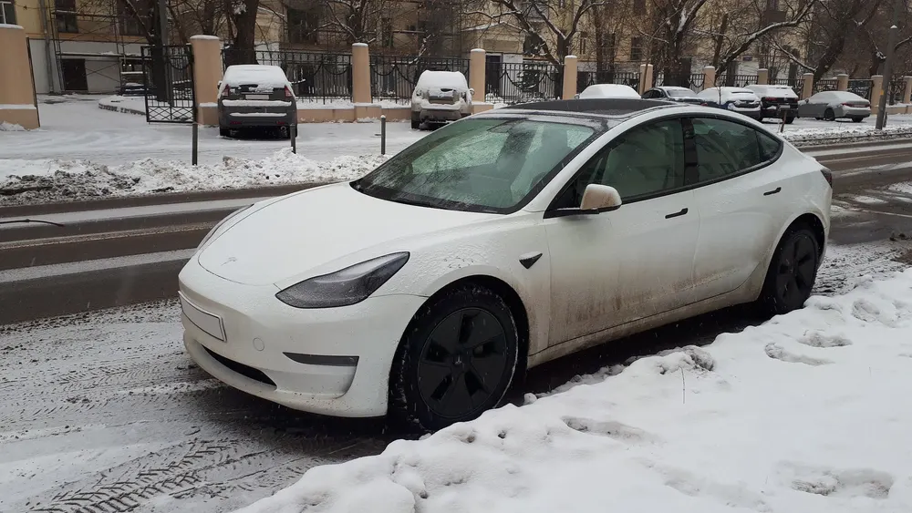 Weißes Tesla am verschneiten Straßenrand im Winter
