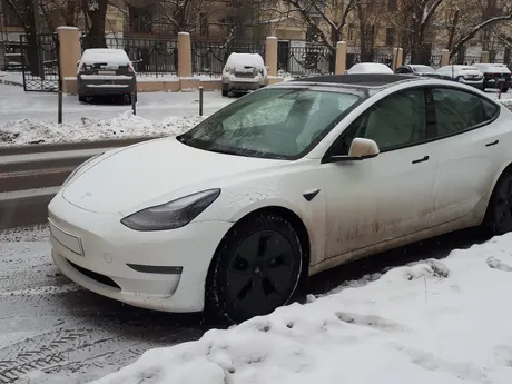 Weißes Tesla am verschneiten Straßenrand im Winter