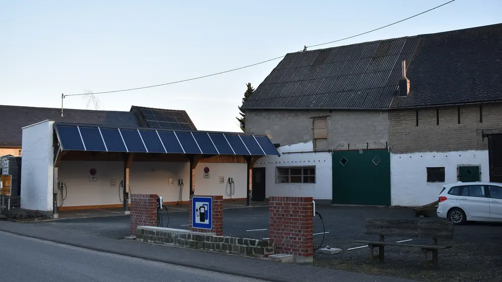 Carport mit Solarmodulen auf dem Dach und mehreren Wallboxen an einer Ladestation in Mörsdorf (Hunsrück), dahinter ein Hausdach mit PV-Anlage